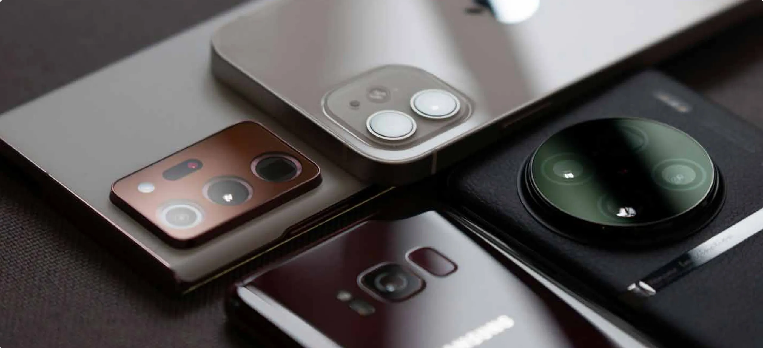 Smartphones de distintas marcas apilados, vista de cámaras traseras